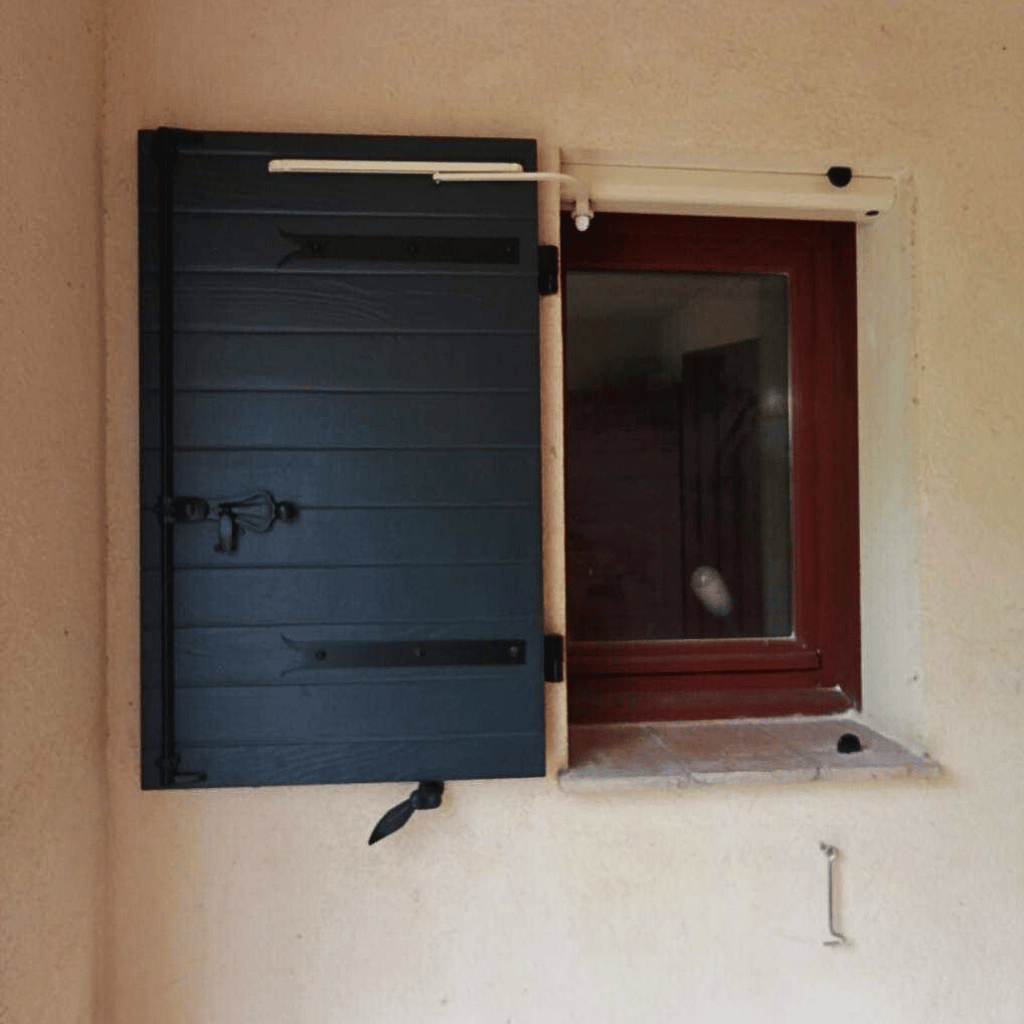 Détail d’un volet battant noir motorisé avec système solaire Yzéa, installé sur une fenêtre en façade.